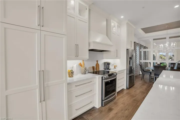 Kitchen featuring stainless steel appliances, sink, pendant lighting, hardwood / wood-style flooring, and a notable chandelier