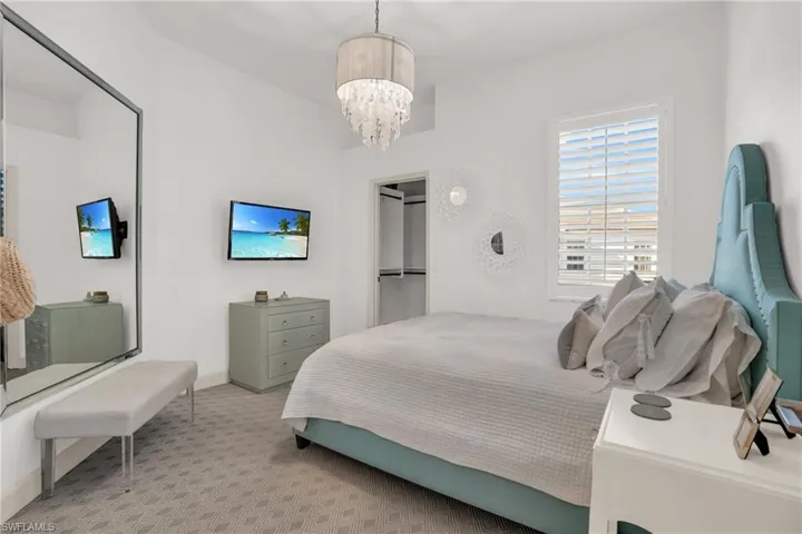 Bedroom with light carpet and a notable chandelier
