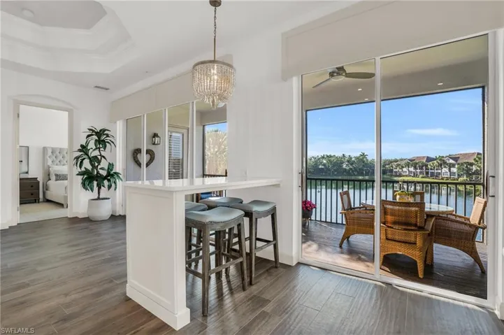 Dining space with a tray ceiling, a water view, dark hardwood / wood-style flooring, and ceiling fan with notable chandelier