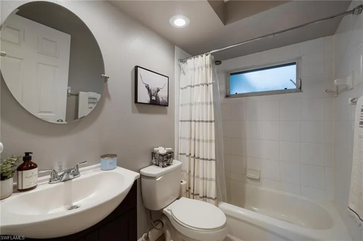 Full bathroom featuring a textured wall, vanity, and shower / bathtub combination with curtain
