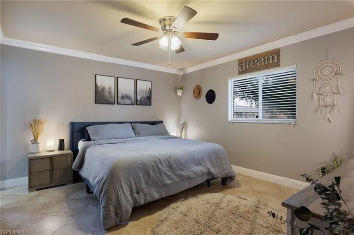 Tiled bedroom featuring ornamental molding and ceiling fan