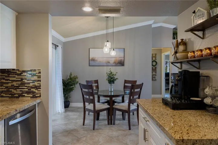 Dining room featuring ornamental molding, lofted ceiling, light tile patterned floors, and a textured ceiling