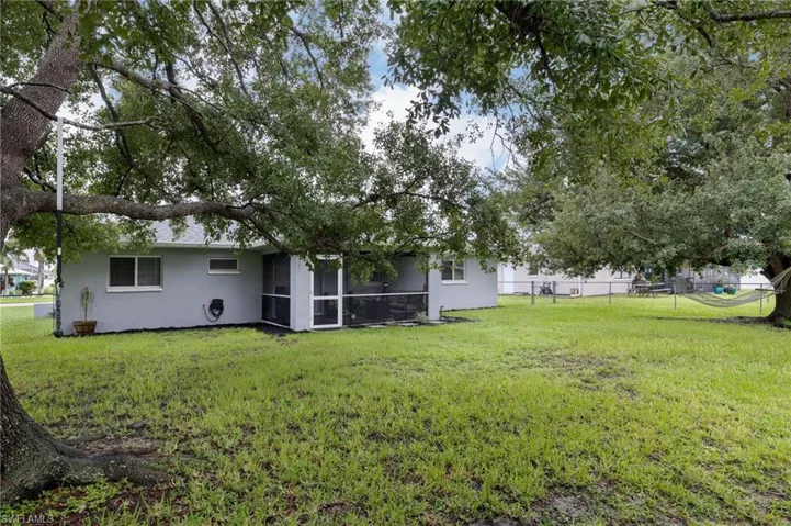 Rear view of house featuring a fenced backyard, stucco siding, and a sunroom