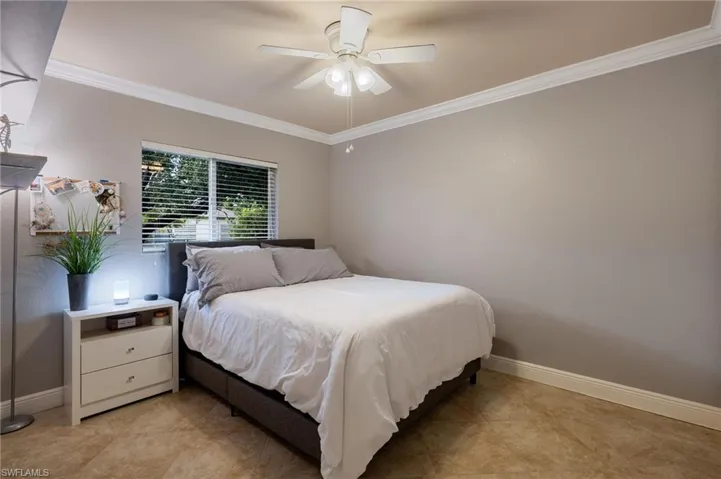 Bedroom featuring crown molding, a ceiling fan, and light tile patterned floors