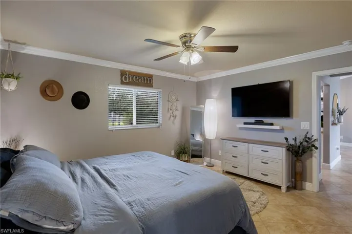 Bedroom with crown molding, ceiling fan, and light tile patterned floors