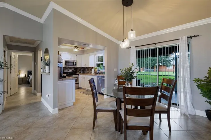 Dining room with light tile patterned floors, ornamental molding, and ceiling fan