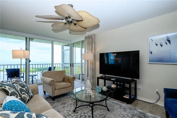 Living room with wood-type flooring, a water view, plenty of natural light, and ceiling fan