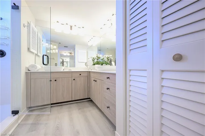 Bathroom featuring dual vanity, walk in shower, and hardwood / wood-style flooring