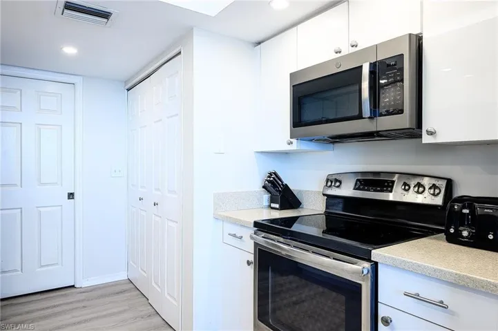 Kitchen featuring appliances with stainless steel finishes, light hardwood / wood-style floors, and white cabinetry