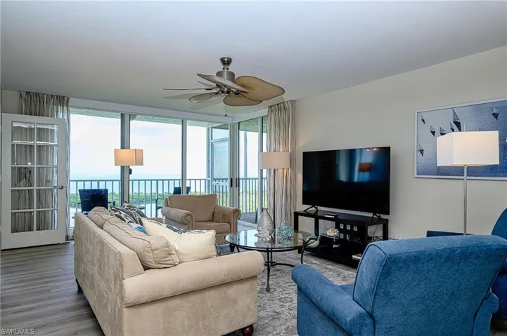 Living room with ceiling fan, a healthy amount of sunlight, a water view, and wood-type flooring