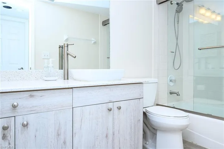 Full bathroom featuring enclosed tub / shower combo, toilet, and vanity