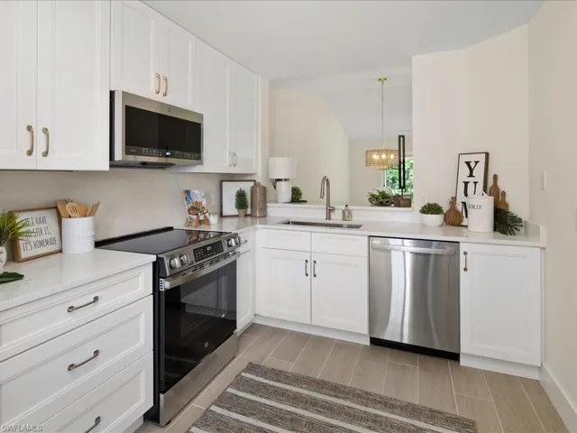 Kitchen featuring sink, lofted ceiling, white cabinets, and stainless steel appliances