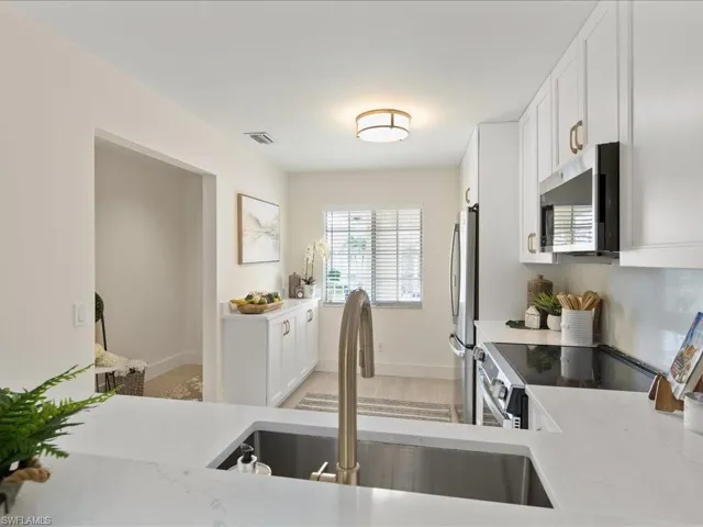 Kitchen featuring white cabinets, stainless steel appliances, light stone countertops, and light hardwood / wood-style flooring