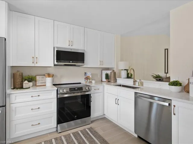 Kitchen featuring sink, white cabinetry, light stone countertops, and stainless steel appliances