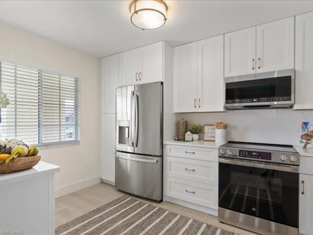 Kitchen with light hardwood / wood-style floors, appliances with stainless steel finishes, and white cabinetry