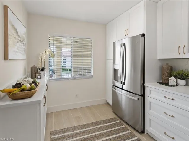 Kitchen with stainless steel fridge, white cabinetry, and light hardwood / wood-style flooring
