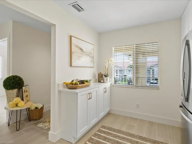 Kitchen with white cabinetry, stainless steel fridge, and light hardwood / wood-style flooring