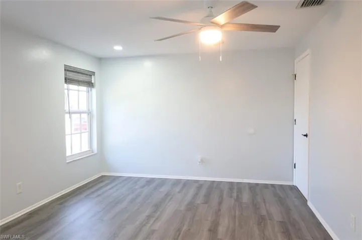 Empty room with dark wood-type flooring, ceiling fan, and recessed lighting