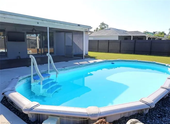 View of pool featuring a fenced backyard, a sunroom, and patio surround