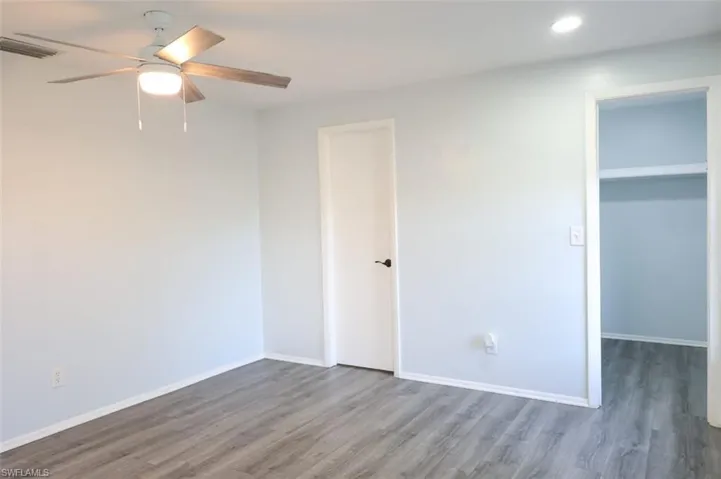 Unfurnished bedroom with a walk in closet, wood finished floors, a ceiling fan, and recessed lighting