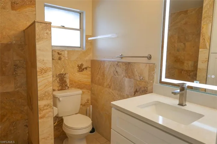 Full bath with vanity, tile walls, and a shower