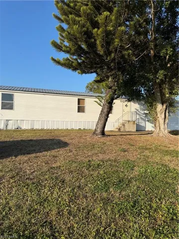 View of side of property featuring a metal roof and a lawn