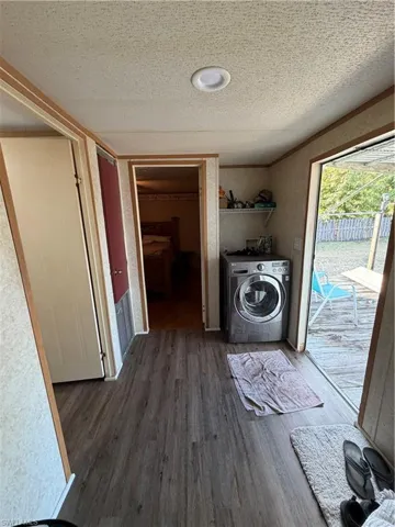 Laundry room featuring washer / clothes dryer, dark wood-type flooring, and a textured ceiling