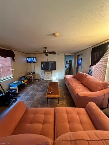 Living area with a textured ceiling and a ceiling fan