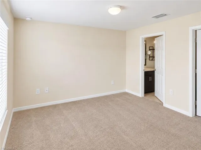 Neutral tone wall paint, light tan carpeting, white window blinds, white flush mount ceiling light, and white interior doors