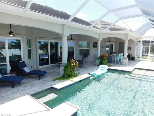 View of swimming pool featuring ceiling fan, glass enclosure, and a patio area