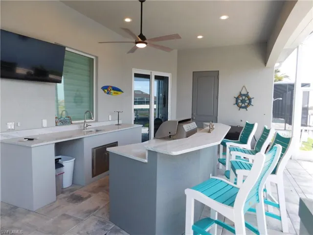 View of terrace featuring a wet bar, exterior kitchen, and ceiling fan