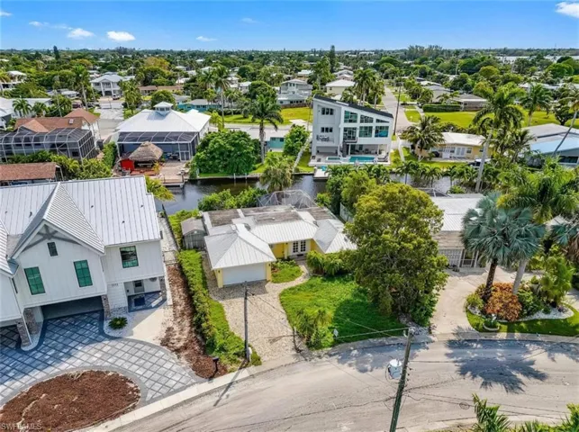 Waterfront property featuring mature tropical landscaping and a paved driveway