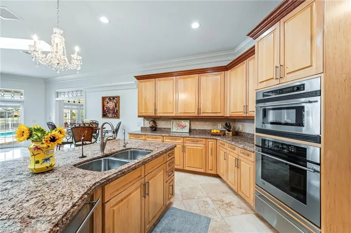 Kitchen with stainless steel double oven, a sink, a warming drawer, tasteful backsplash, and a notable chandelier