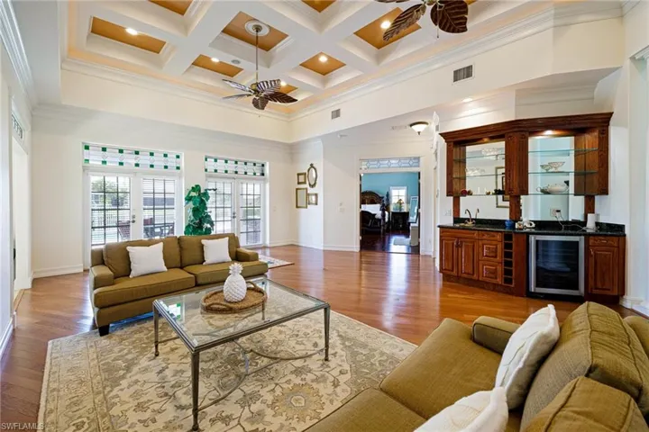 Living area with beverage cooler, a high ceiling, ceiling fan, visible vents, and indoor wet bar