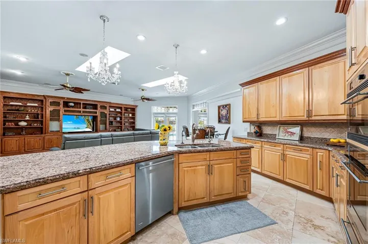 Kitchen featuring crown molding, a sink, ceiling fan with notable chandelier, dishwasher, and backsplash