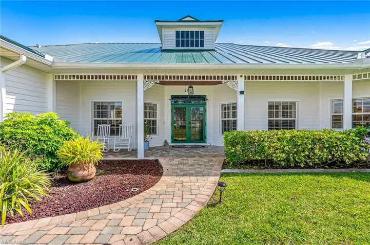 Entrance to property featuring a lawn, covered porch, and metal roof