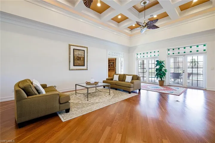 Living room with beam ceiling, baseboards, a towering ceiling, coffered ceiling, and a ceiling fan