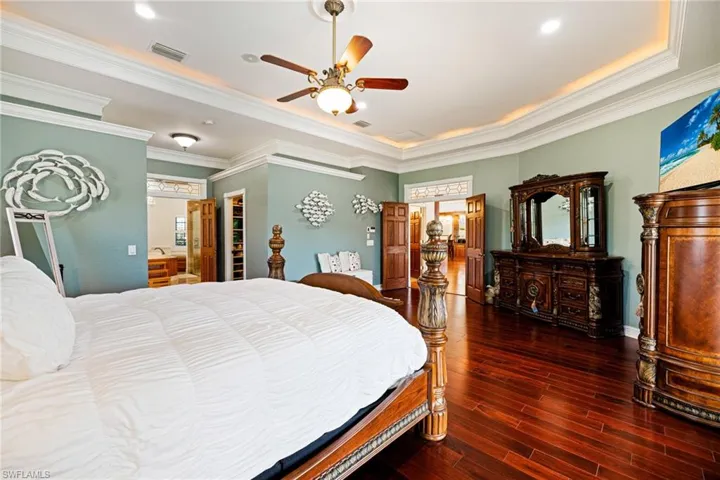 Bedroom featuring visible vents, wood finished floors, a raised ceiling, and crown molding