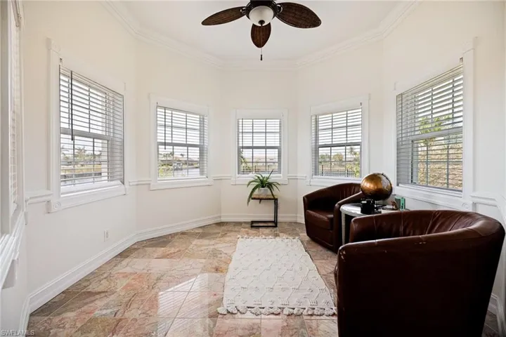 Living area off the master bedroom with a ceiling fan, baseboards, and ornamental molding