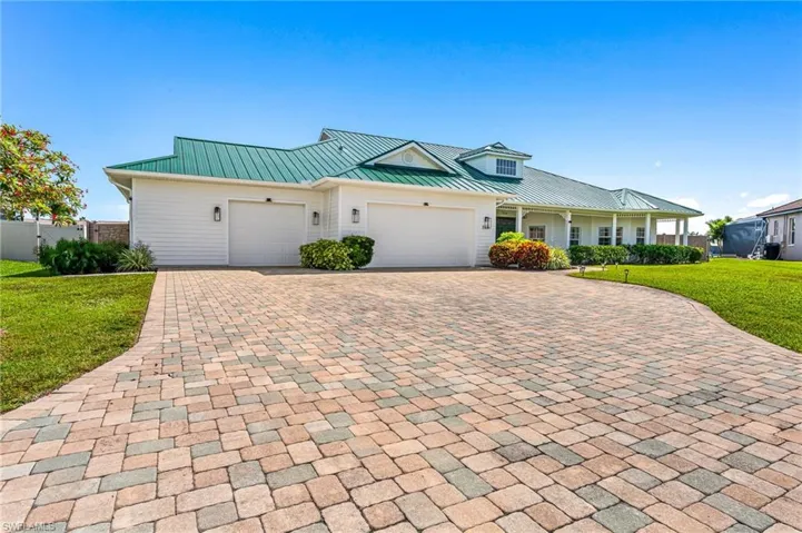 View of front of house with decorative driveway, a front lawn, an attached garage, metal roof, and a standing seam roof