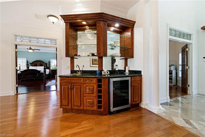 Bar with a sink, wet bar, ceiling fan, crown molding, and beverage cooler