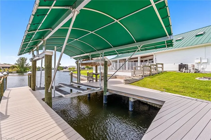 View of dock featuring cooling unit, a yard, boat lift, and a water view
