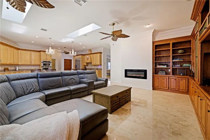 Living area with recessed lighting, visible vents, crown molding, a skylight, and a glass covered fireplace