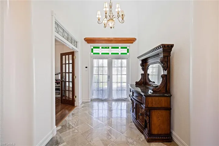 Foyer with marble finish floor, baseboards, a notable chandelier, and french doors