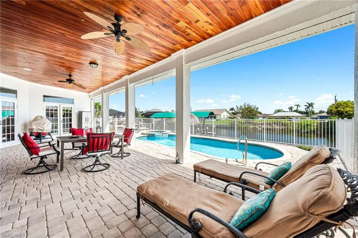 View of patio with outdoor lounge area, a ceiling fan, a pool with connected hot tub, and a fenced backyard
