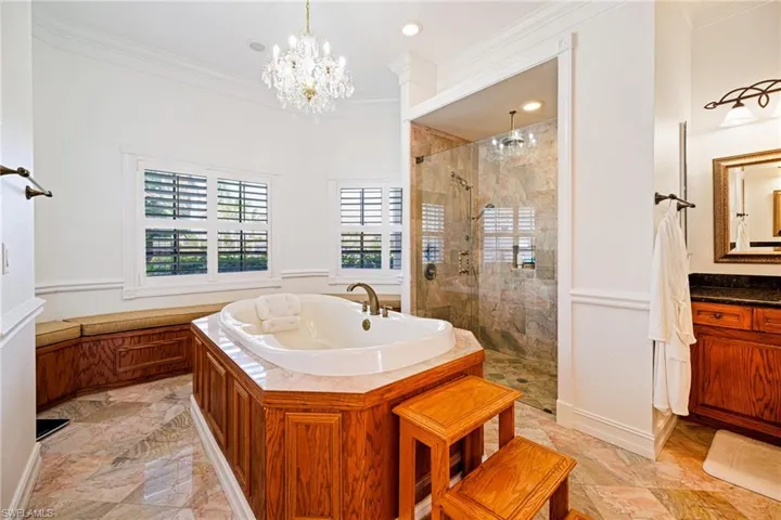 Full bathroom featuring a tile shower, vanity, crown molding, a chandelier, and a garden tub