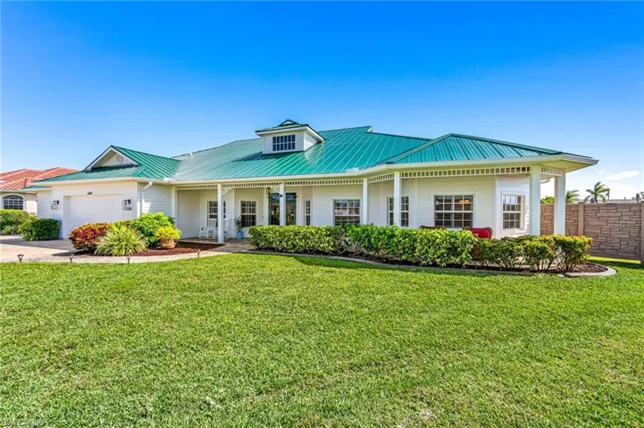 View of front of property featuring a standing seam roof, a garage, a front yard, and metal roof