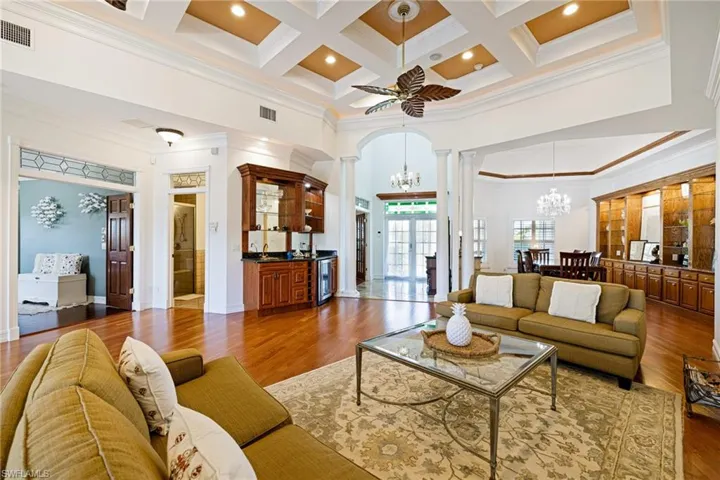 Living room featuring coffered ceiling, visible vents, ornamental molding, beam ceiling, and decorative columns