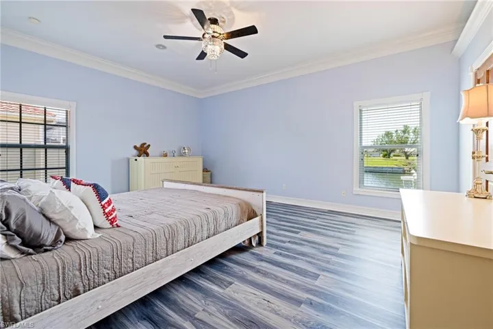 Bedroom with ceiling fan, baseboards, crown molding, and wood finished floors
