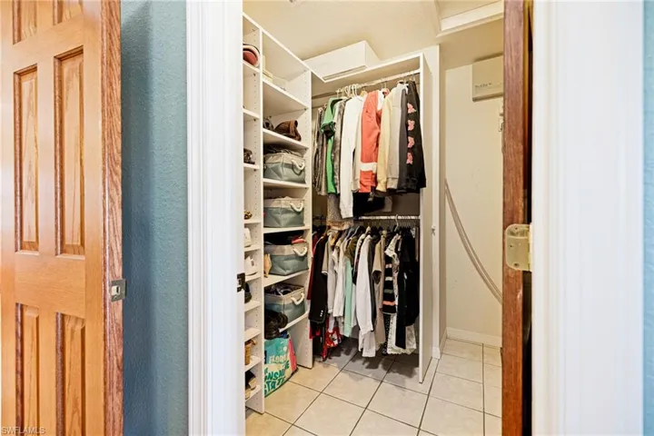 Primary his/her closets - featuring tile patterned flooring